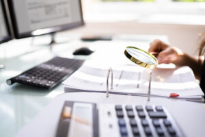 Person Examining Paper Using Magnifier Glass. Fraud Investigation